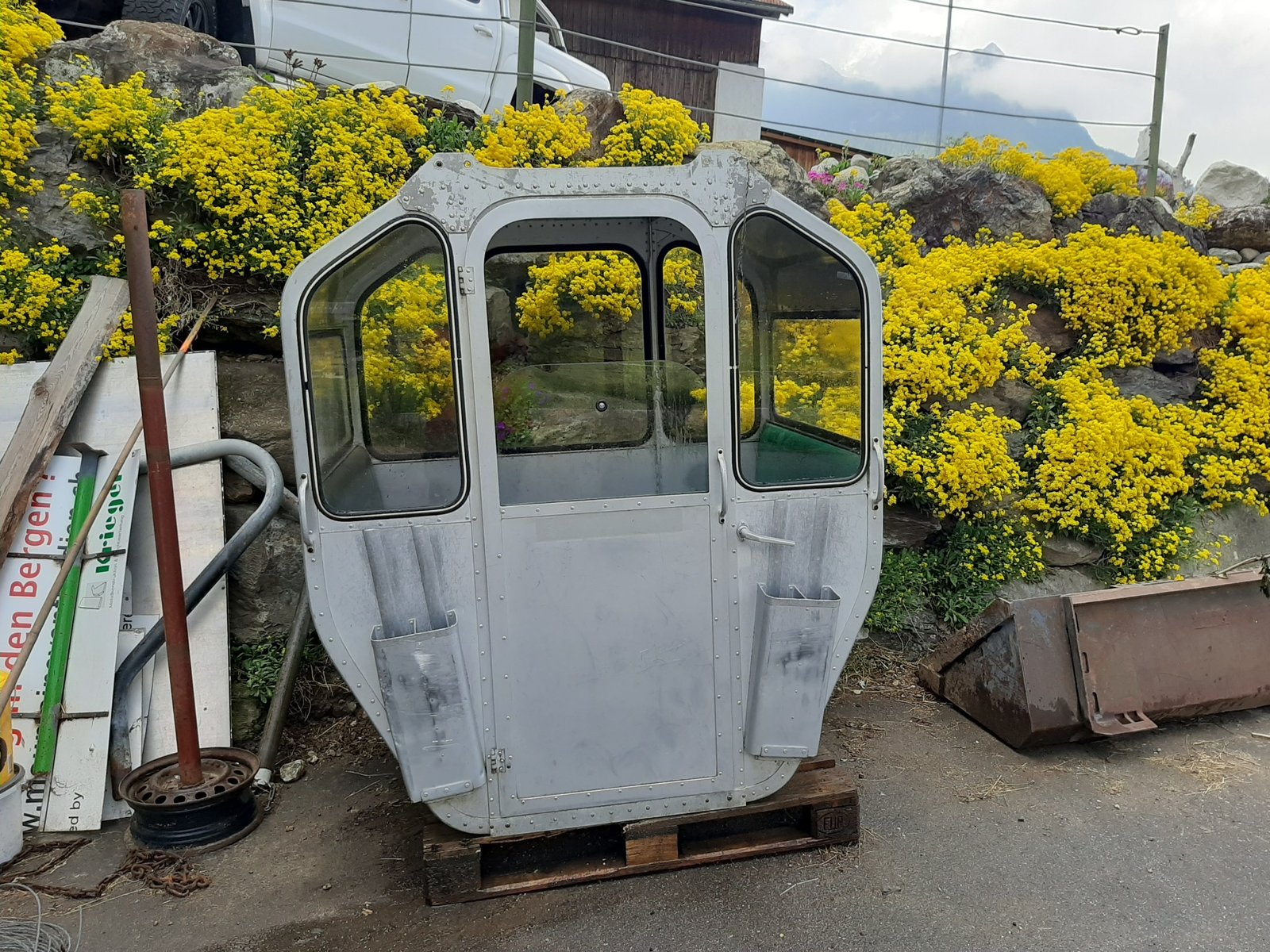 Silberne Gondelkabine vor gelben Blumen