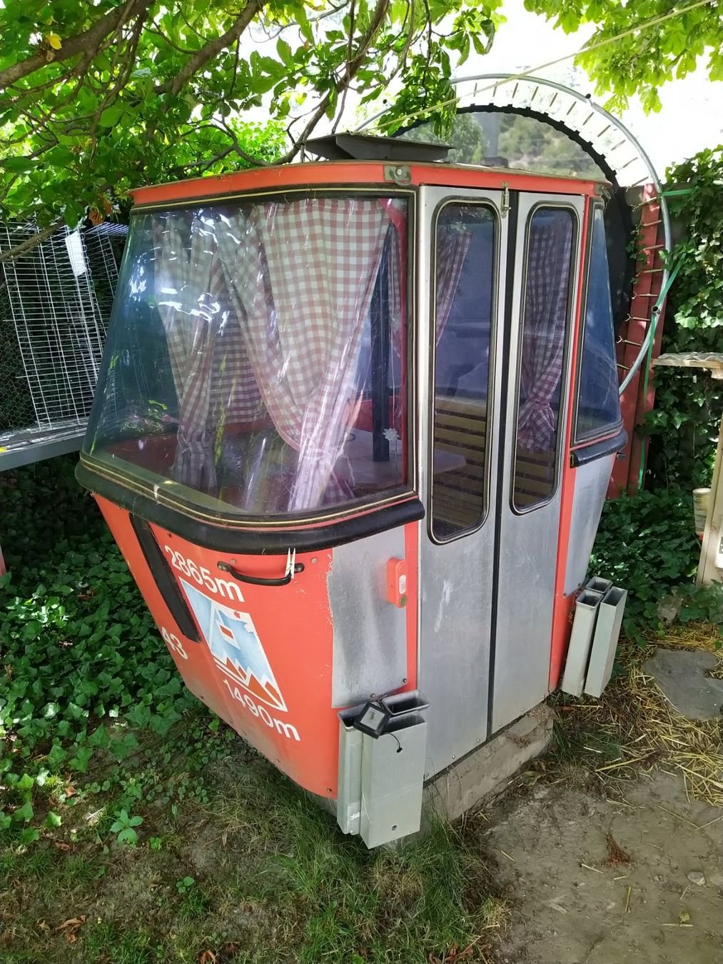 Gondelkabine mit karierten Vorhängen im Garten